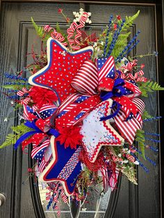 a patriotic wreath with red, white and blue decorations on the front door for fourth of july