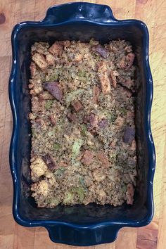 a casserole dish with meat and vegetables in it sitting on a wooden table