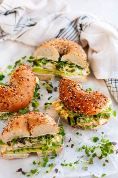 four sandwiches with different toppings sitting on top of a white paper towel next to a napkin