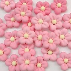 pink and white flowers are arranged together on a white tablecloth with yellow dots in the center