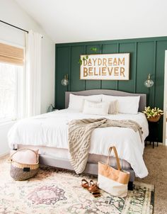 a bedroom with green painted walls and a white bed in the middle, along with a large rug on the floor