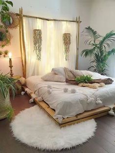 a white bed sitting in a bedroom next to two potted plants on either side of the bed