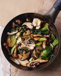 mushrooms, spinach and other vegetables are cooking in a pan on top of a table