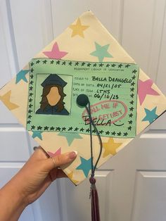 a hand holding up a graduation cap with the image of a woman's face on it