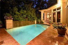 an outdoor swimming pool at night with lights on and flowers in the planters next to it