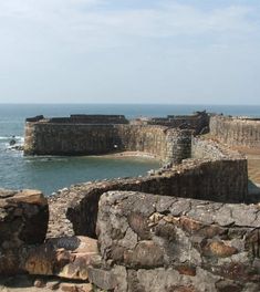 an old stone wall next to the ocean