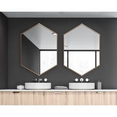 two mirrors hanging on the wall above sinks in a bathroom with grey walls and wooden cabinets