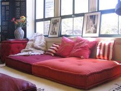 a red couch sitting in front of a window