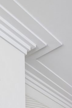 the corner of a white room with a clock on it's face and ceiling