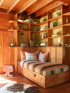 a bed sitting in the middle of a room next to a book shelf filled with books