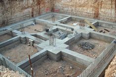 an unfinished building with concrete blocks in the middle and people standing around it on either side