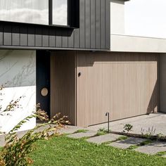 a modern house with two garages and grass in the front yard, next to it