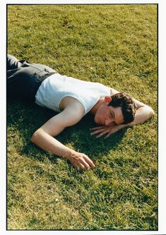 a man laying in the grass with his hands on his chest and head resting on his stomach