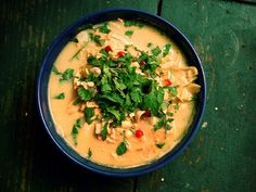 a blue bowl filled with soup on top of a wooden table