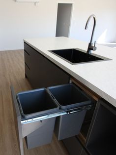 two trash cans are in the middle of a kitchen counter