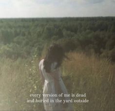 a woman standing in the middle of a field with her hair blowing in the wind