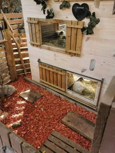 a chicken coop with red mulch on the floor and wooden crates in front of it