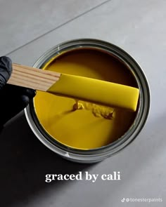 a person holding a paint brush in a yellow can