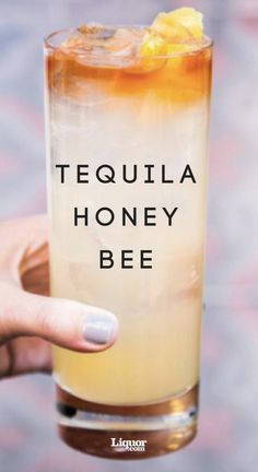 a person holding up a tall glass with honey bee in it and the words tequila honey bee