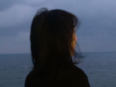 a blurry photo of a woman looking out at the ocean