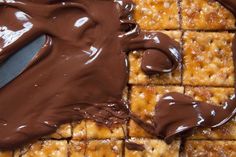 chocolate spread on top of crackers with a spatula in the foreground and peanut butter squares to the side