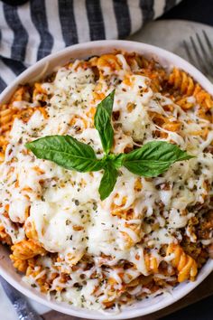 a white bowl filled with pasta covered in cheese and basil garnished with parmesan