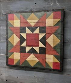 a wooden wall hanging with a colorful star design on it's side and wood planks in the background