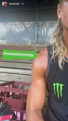 a man with long hair wearing a black shirt and green monster energy sticker on his chest