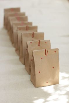 small brown paper bags lined up on the floor with red hearts drawn on each bag