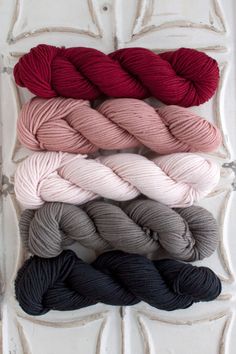 four skeins of yarn in various colors on a white surface with an old door