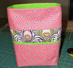 a pink and green bag sitting on top of a table next to a pair of scissors