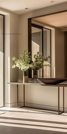 a vase with flowers on a table in front of a large mirror and door to another room