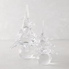 two clear glass vases sitting next to each other on top of a white table