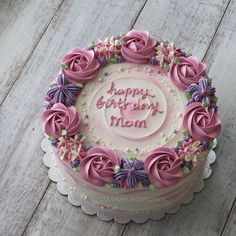 a birthday cake with pink frosting and purple flowers