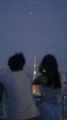 two people are looking at the view of the eiffel tower and the moon