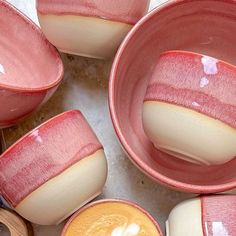 there are many pink bowls and spoons on the table