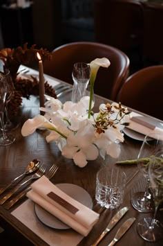 the table is set with white flowers and silverware