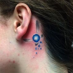 a woman's behind the ear tattoo with blue circles