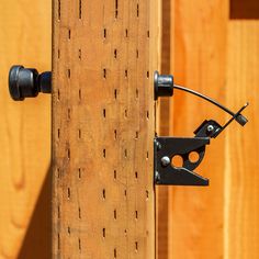 a close up of a wooden fence with two black latches on the handle and one metal hook