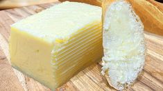 a piece of cheese sitting on top of a wooden cutting board next to a loaf of bread