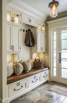 an entryway with white cabinets and wooden bench