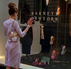 a woman in a purple dress is looking at shoes on display behind a glass window