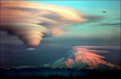 an airplane flying in the sky over a snow covered mountain with clouds and a bird