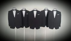 four black tuxedos are lined up in front of each other on white sticks