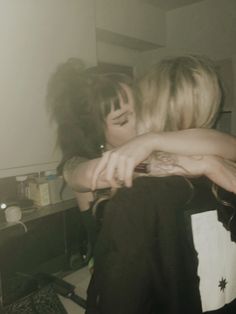 two women hugging each other in front of a mirror