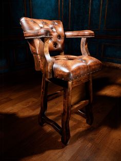 a leather chair sitting on top of a hard wood floor next to a blue wall