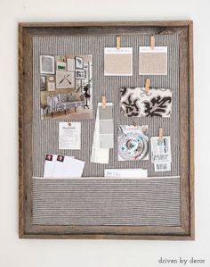 a wooden frame with papers, pictures and other items on it hanging on the wall