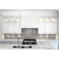 a kitchen with white cabinets and marble counter tops