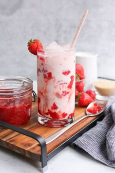 two glasses filled with strawberries on top of a wooden tray