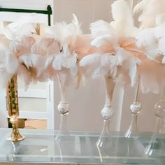 there are several tall vases with white feathers on the top and one is filled with wine glasses